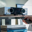 Onkyo Muse Y-50 Network Integrated Amplifier - Silver - lifestyle view of unit on shelf with hand holding remote in foreground