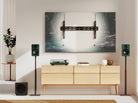 Modern living room with a TV mounted on the wall, speakers, and a wooden cabinet.