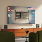 Modern living room with a large TV mounted on the wall, speakers, and green chairs.