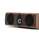 A modern wood-grain center channel speaker with two large black woofers and a central black tweeter, shown from a three-quarters angle on a white background.