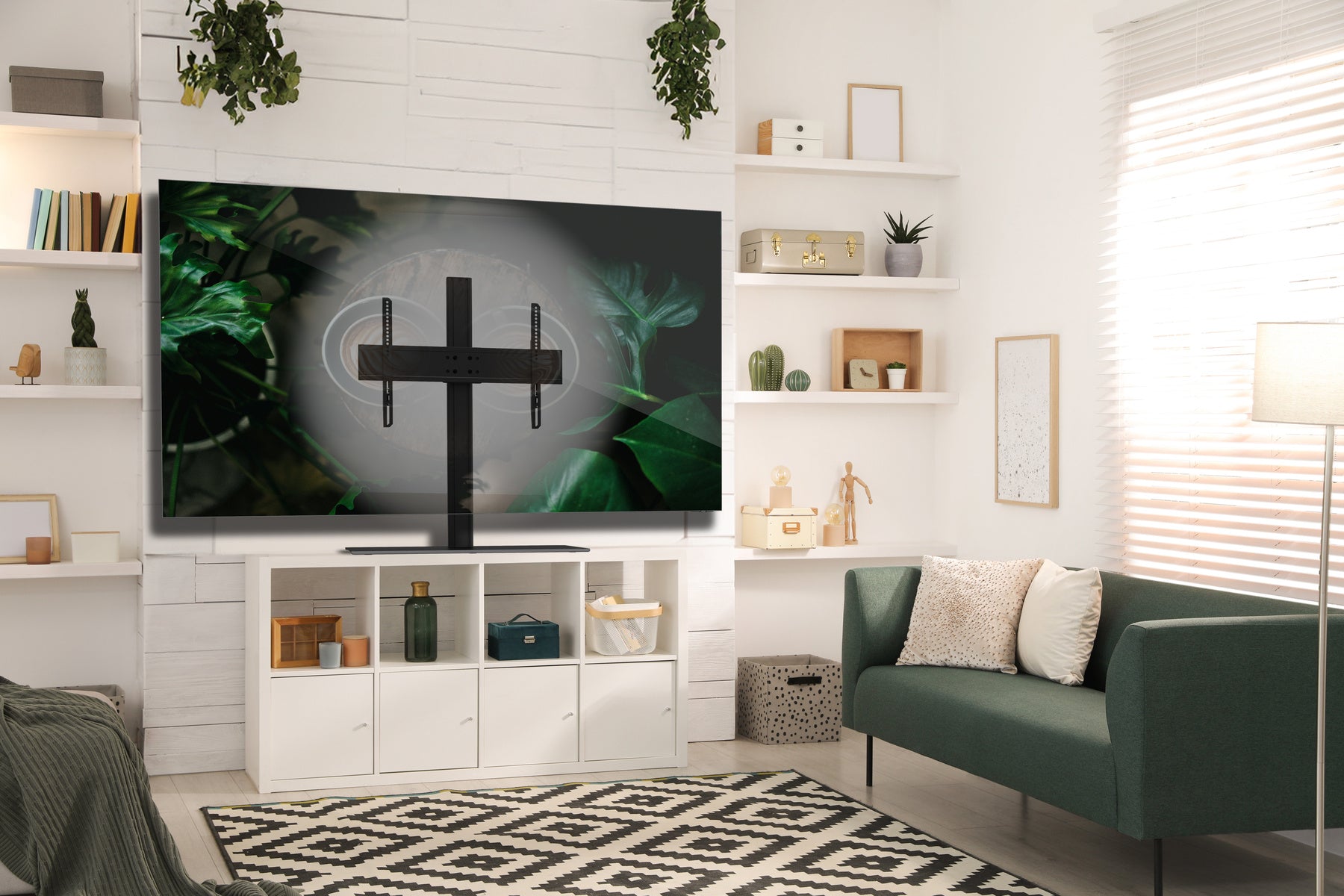 Modern living room with a TV on a white entertainment console, green sofa, and decorative shelves.