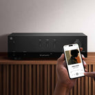 Yamaha R200A 2-Channel Hi-Fi Stereo Receiver with Bluetooth - Black - lifestyle photo of unit on cabinet with hands holding a phone selecting music in foreground