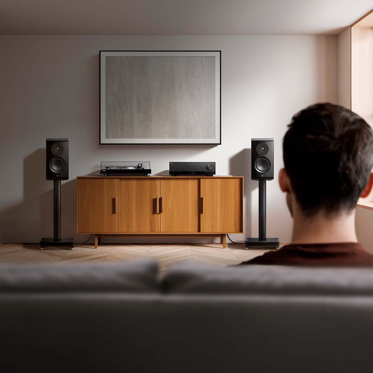Yamaha R200A 2-Channel Hi-Fi Stereo Receiver with Bluetooth - Black - lifestyle photo of unit on cabinet next to record player with couch and back of a man's head in foreground