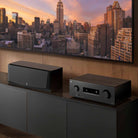 Yamaha RX500A 5.2-Channel AV Receiver - lifestyle image of unit on cabinet to right of speaker and below TV front view angled left