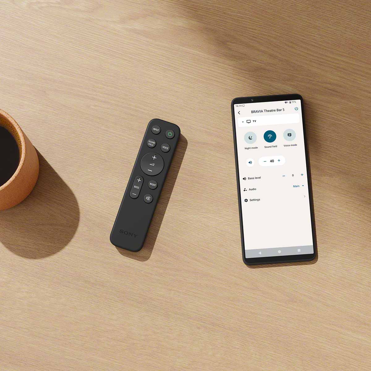 Sony BRAVIA Theater Bar 5 Soundbar remote on table to left of smartphone showing Bravia App