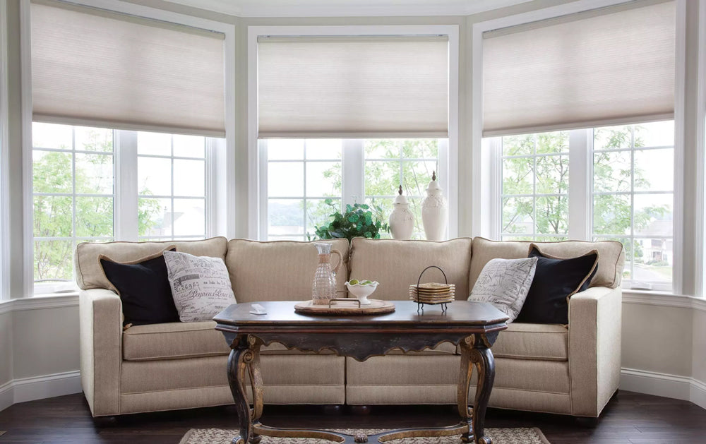Living room with a sofa, coffee table, and large windows with blinds.