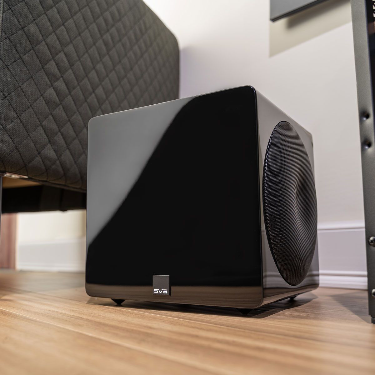 SVS 3000 Micro Subwoofer, black, in a room next to ottoman