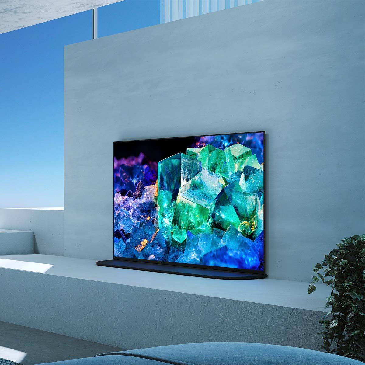 Sony BRAVIA XR A95K 4K OLED Television, on top of a media stand up against a concrete wall in modern living room