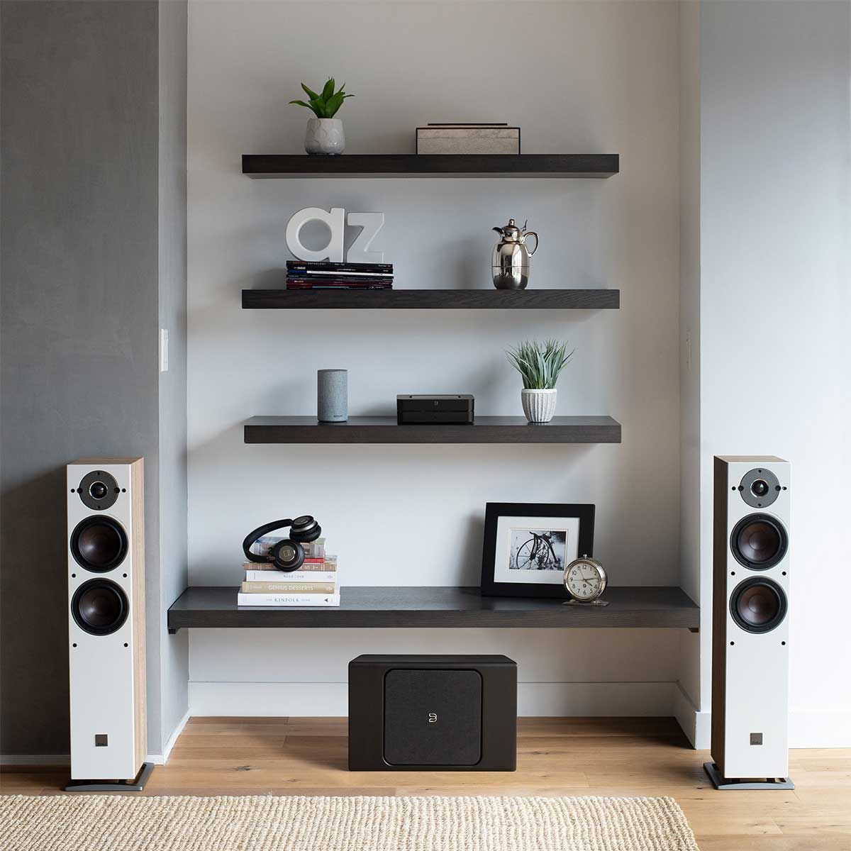Bluesound PowerNode Wireless Music Streaming Amplifier, Black, on shelf between two white floorstanding speakers