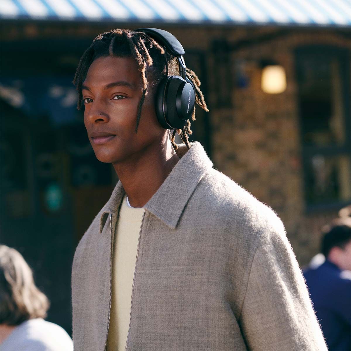 Young male wearing & demonstrating the use of the Px7 S2 Premium Wireless Over-Ear Headphones in Black.