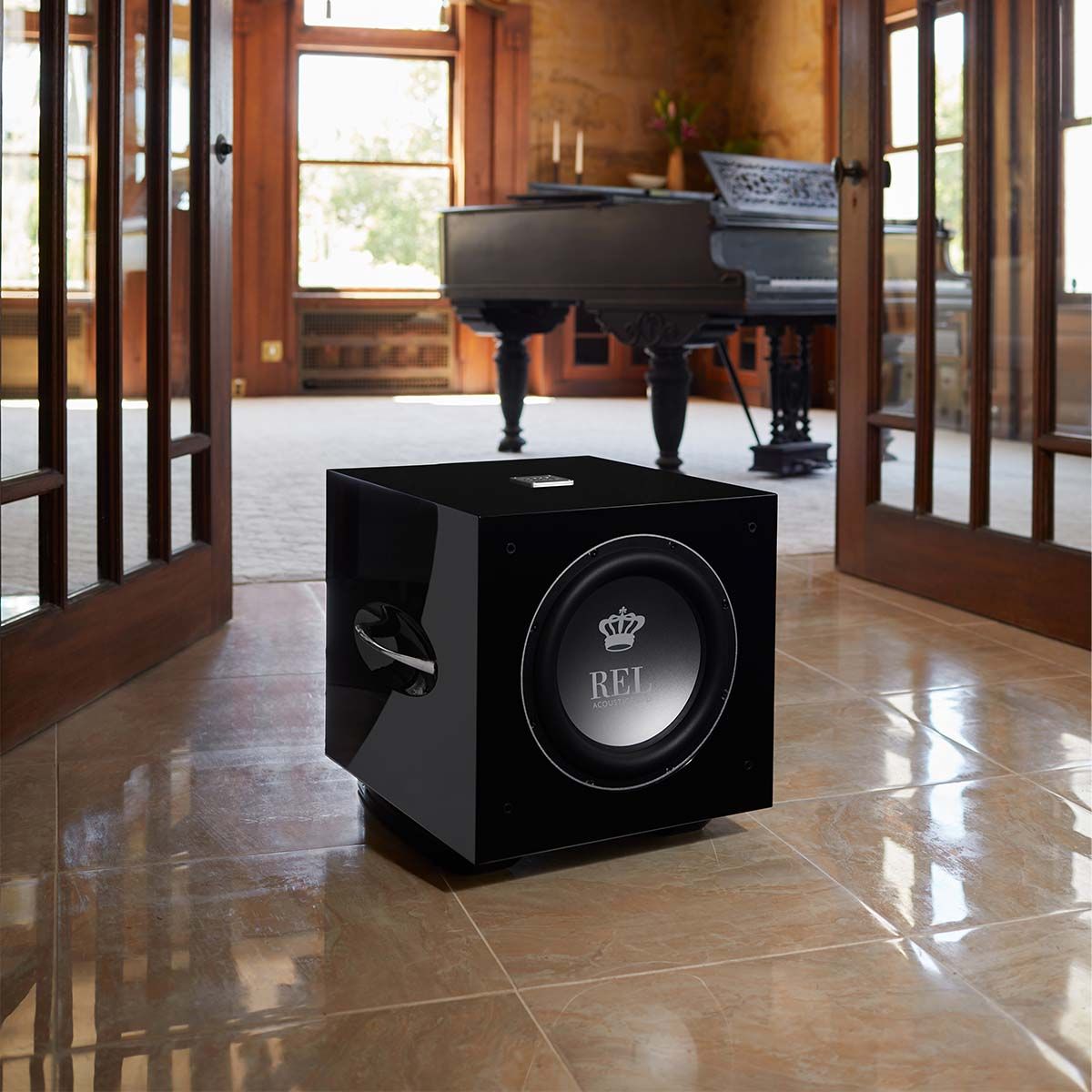 REL Acoustics S/812 Subwoofer, Black, in a room with a piano