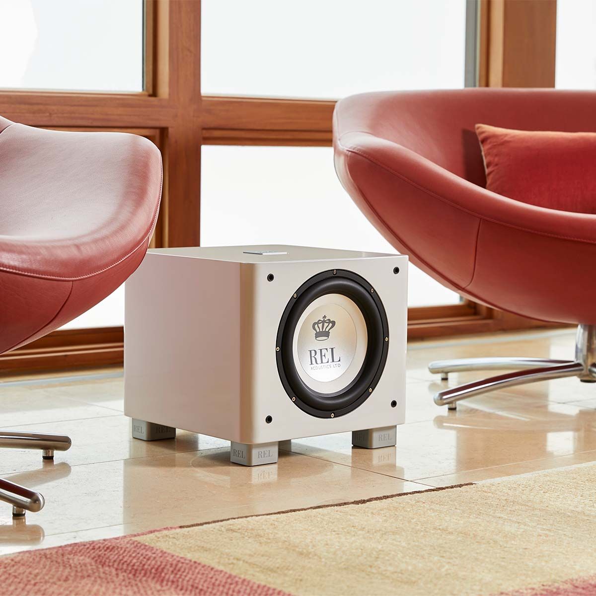 REL Acoustics T/9x Subwoofer, white, in a fancy living room between two fancy chairs