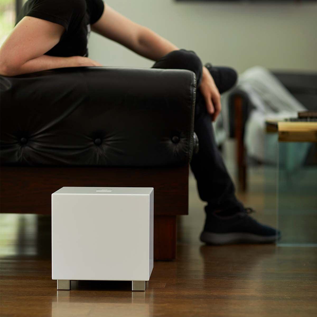 REL Acoustics Tzero MKIII Subwoofer, White, in a living space beside a dark leather couch