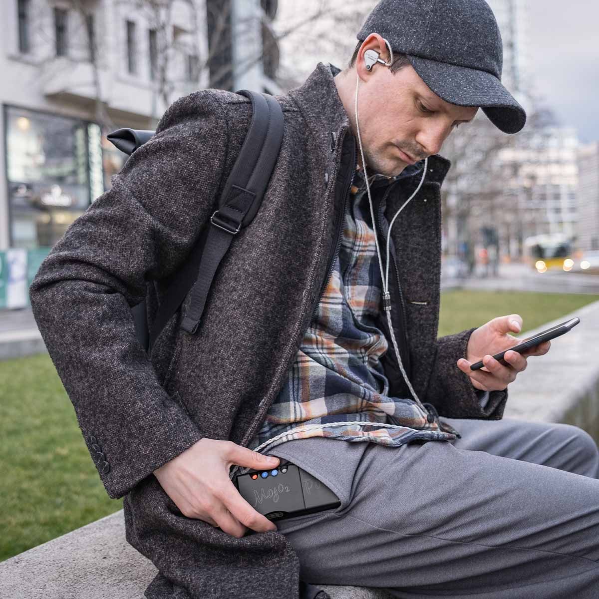 Man listening to in-ear headphones connected to Chord Mojo 2