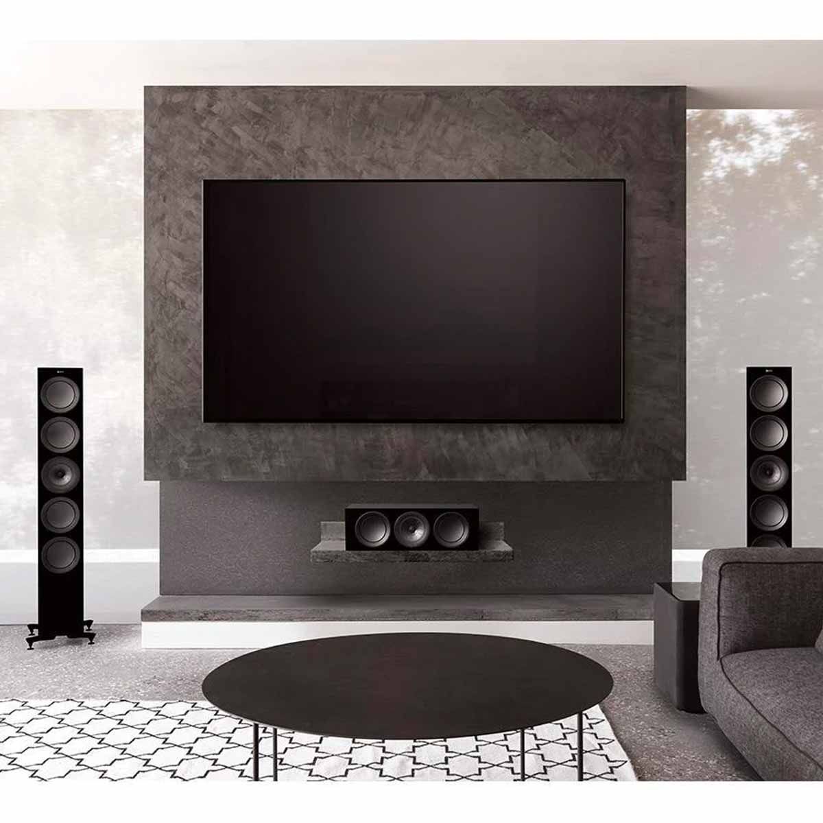 KEF R11 Floorstanding Loudspeaker - Black - in room with TV mounted on stone accent wall