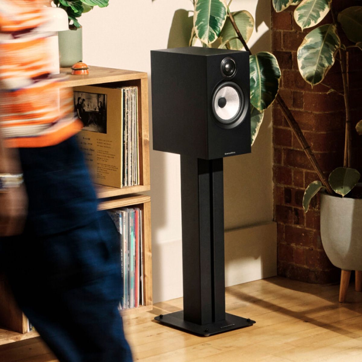 Bowers & Wilkins 607 S3 Bookshelf speaker on stand in a living room beside a media cabinet