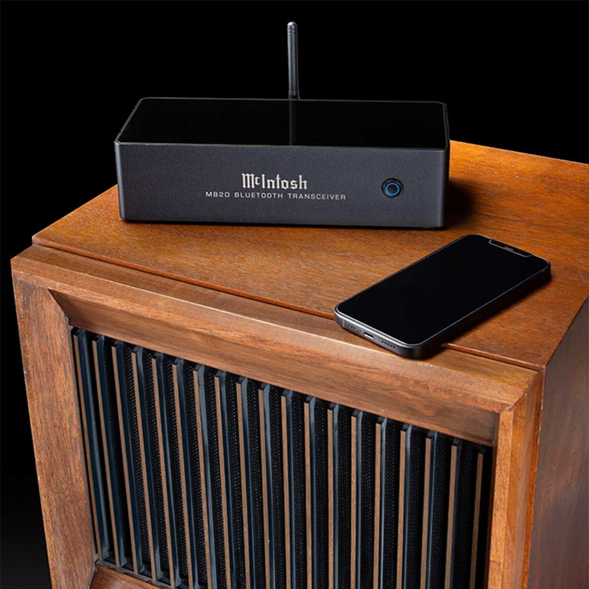 McIntosh MB20 Bluetooth Transceiver, black, front angle on wood side table and beside smartphone
