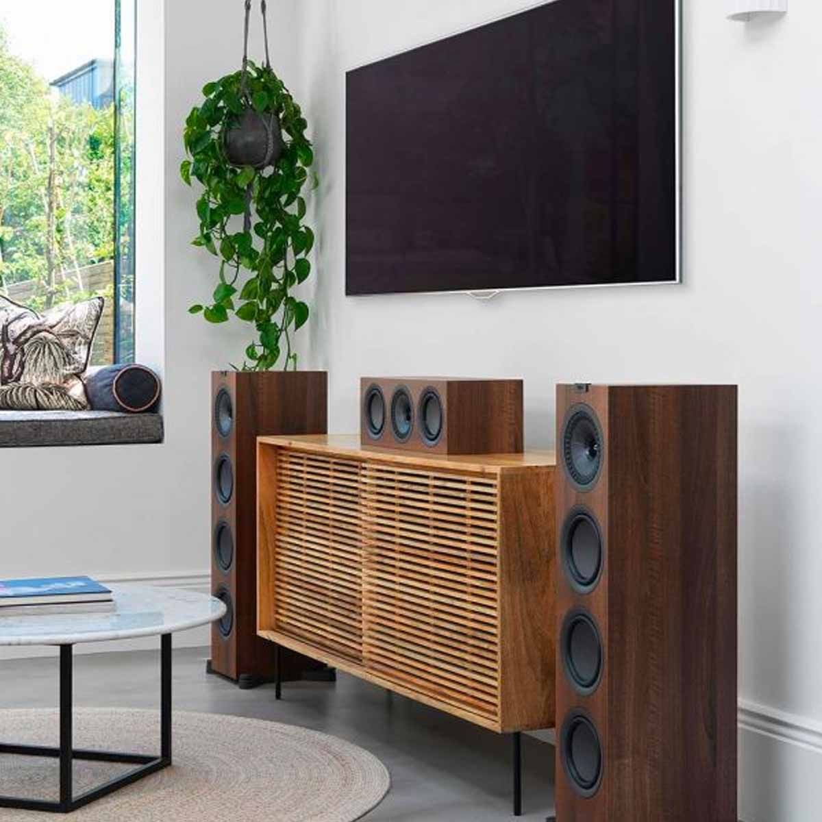 KEF Q250C Center Channel Speaker - Walnut - angled view on entertainment stand under TV with matching tower speakers