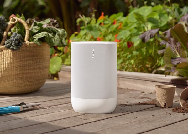 Sonos Move 2 in white outside on a deck surrounded by plants and gardening tools