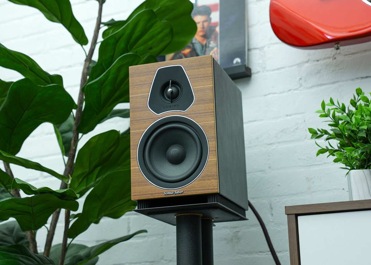 Sonus Faber Lumina II bookshelf speaker on a stand in front of a plant and brick wall