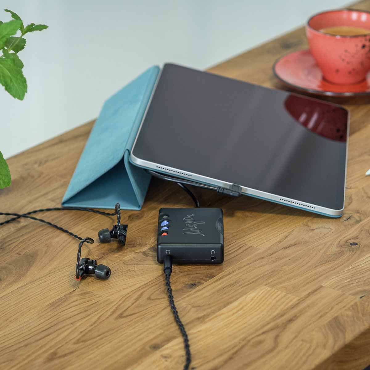 Chord Mojo 2 connected to  tablet and in-ear headphones sitting on desk