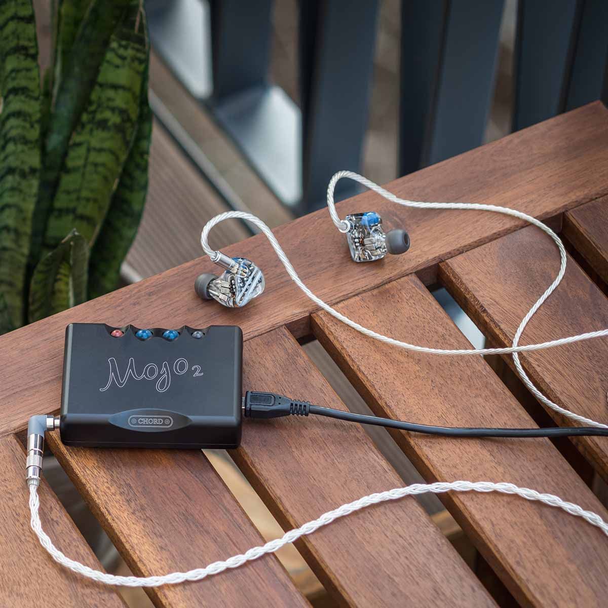 Chord Mojo 2 connected to in-ear headphones sitting on patio table outside