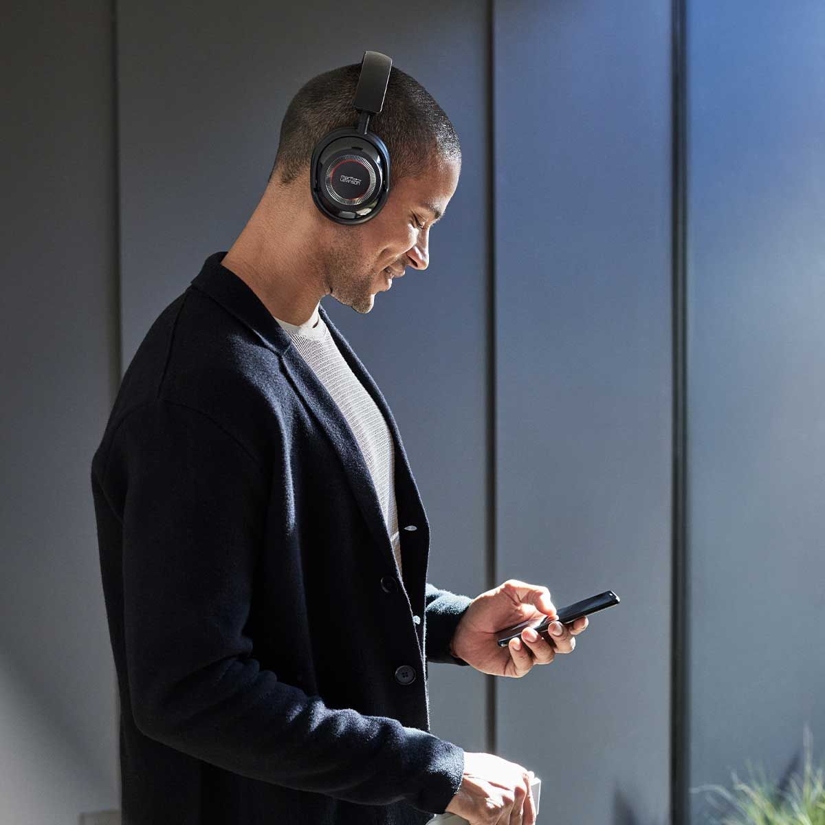 Male model wearing a pair of Mark Levinson № 5909 Premium Hi-Res Wireless ANC Over-Ear headphones at the airport.