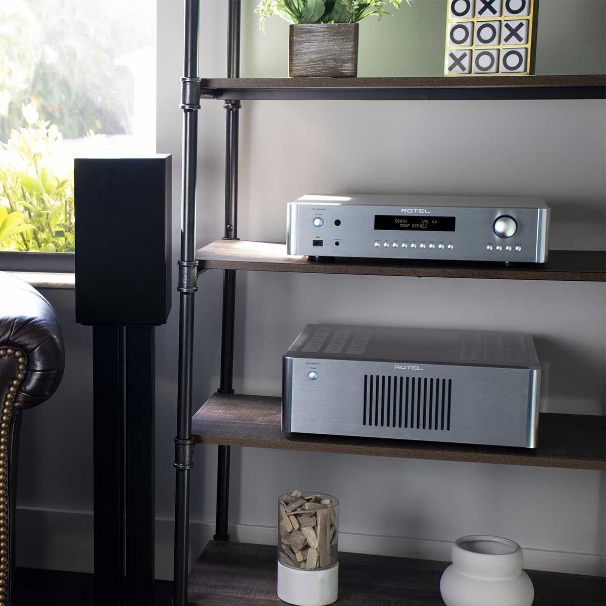 Rotel RC-1572 MKII Stereo Preamplifier, Silver, on an audio rack with a Rotel power amplifier beside a bookshelf speaker