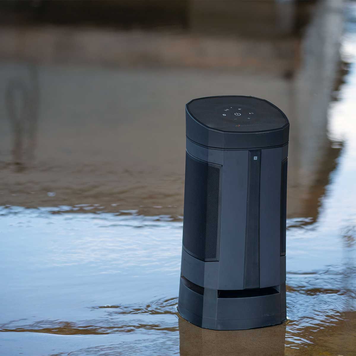 Close-up shot of the Soundcast VG5 Portable Waterproof Bluetooth Speaker's front view in water at the beach.