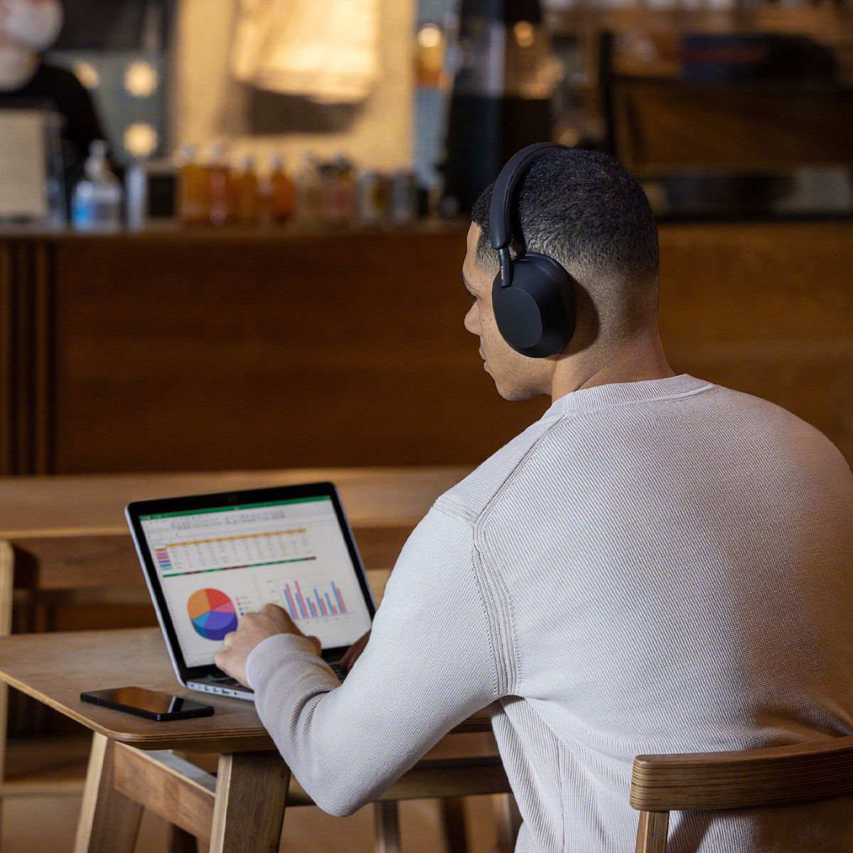Lifestyle image of man wearing WH-1000XM5 headphones while working on computer