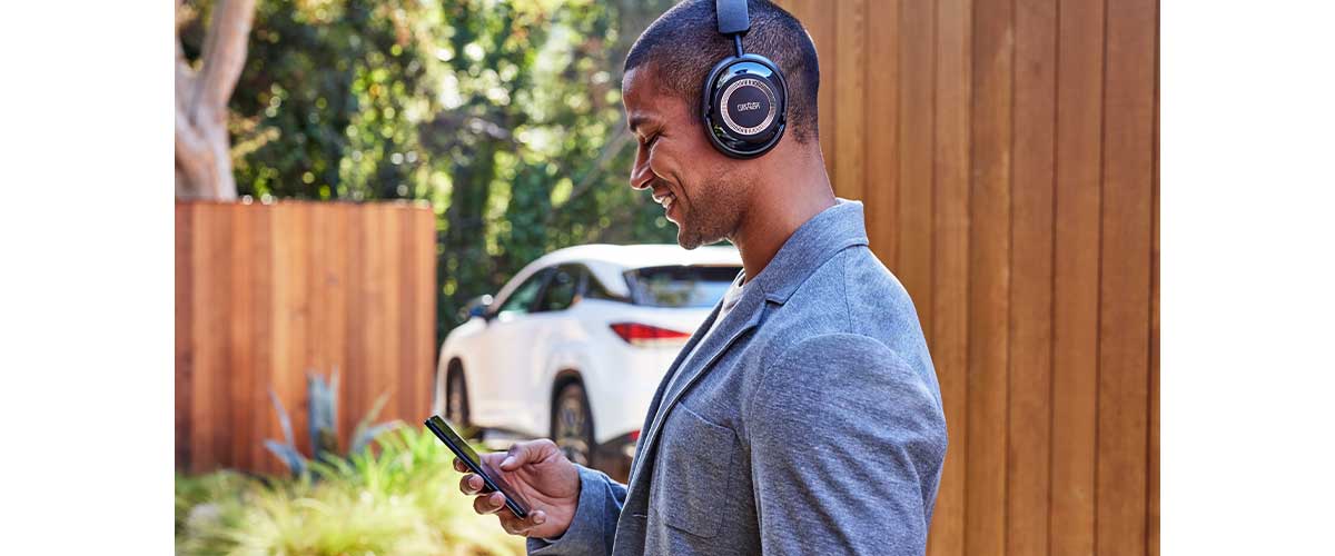 A male model wearing a pair of Mark Levinson № 5909 headphones outside and staring at his smartphone.