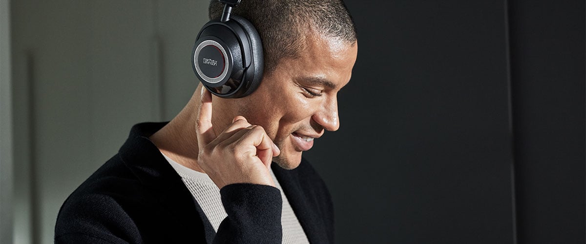 Close up of a male model wearing a pair of Mark Levinson № 5909 headphones and pressing a button on the ear cup.