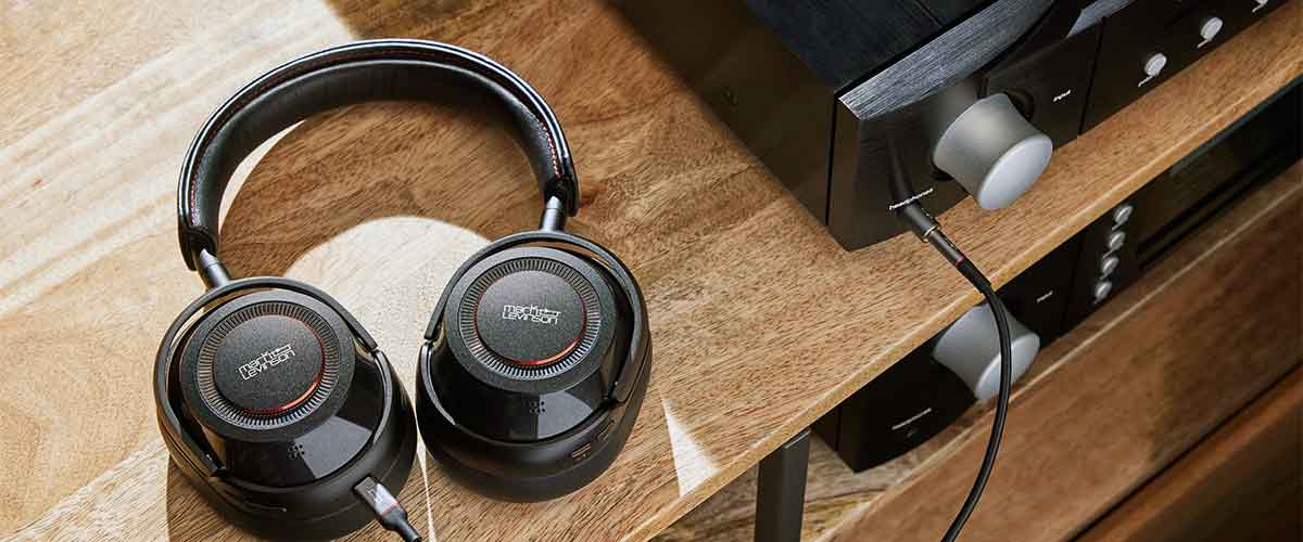 A close up shot of the Mark Levinson № 5909 headphone connected to a stereo amplifier and laying on a desk.