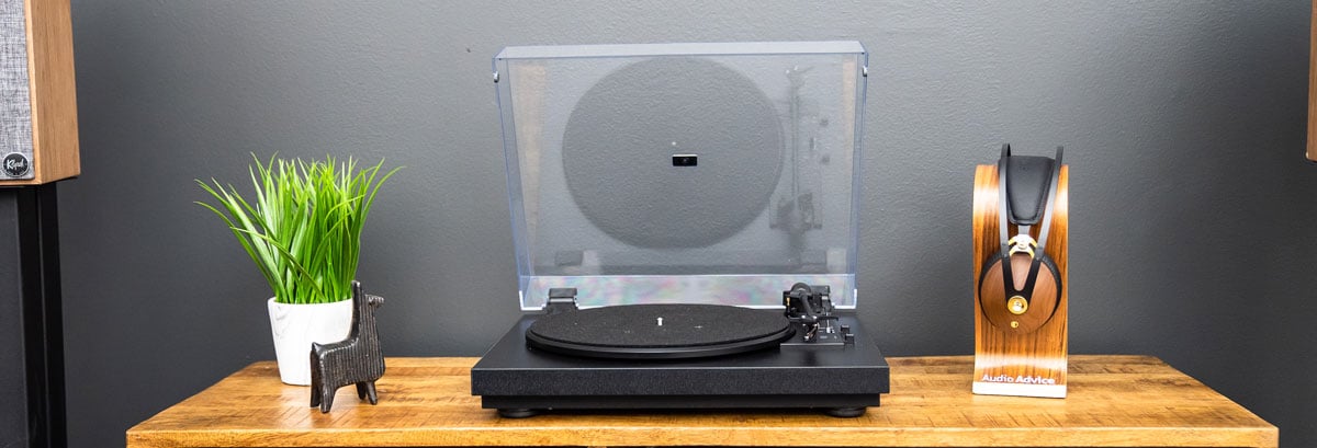 Pro-Ject Automat A1 turntable on a wooden stand with headphones beside of it