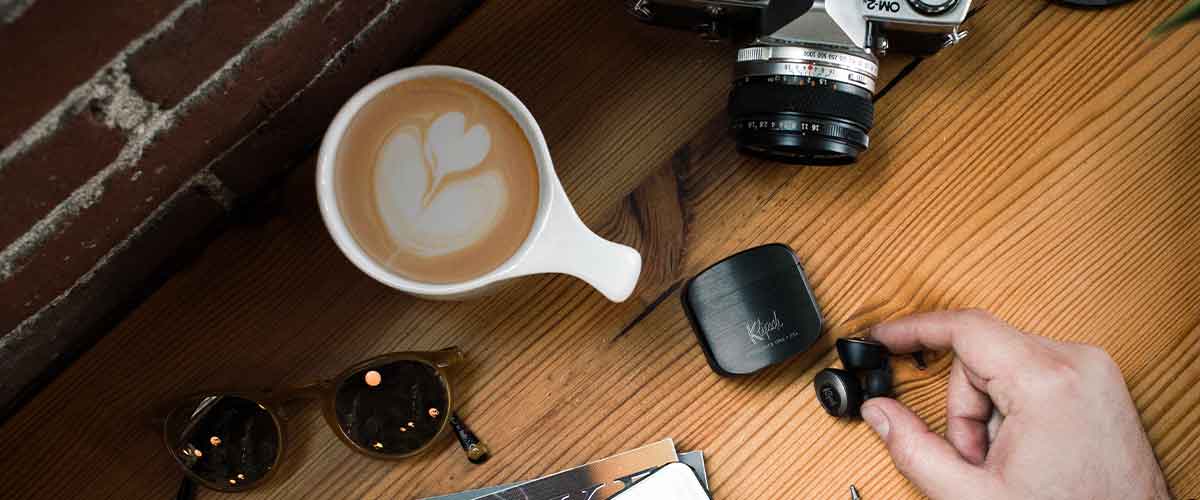 Klipsch T5 II True Wireless In-Ear Headphones on a desk next to a cup of coffee