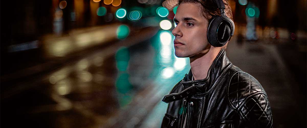 male model wearing a pair of Bowers and Wilkins PX7 Carbon Edition noise cancelling headphones in a noisy urban street