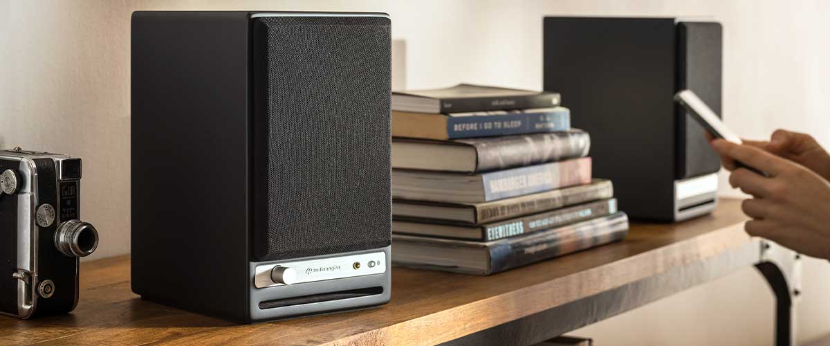 Close up shot of someone bluetoothing music fomr a smartphone to a pair of Audioengine HD4 powered bookshelf speakers.