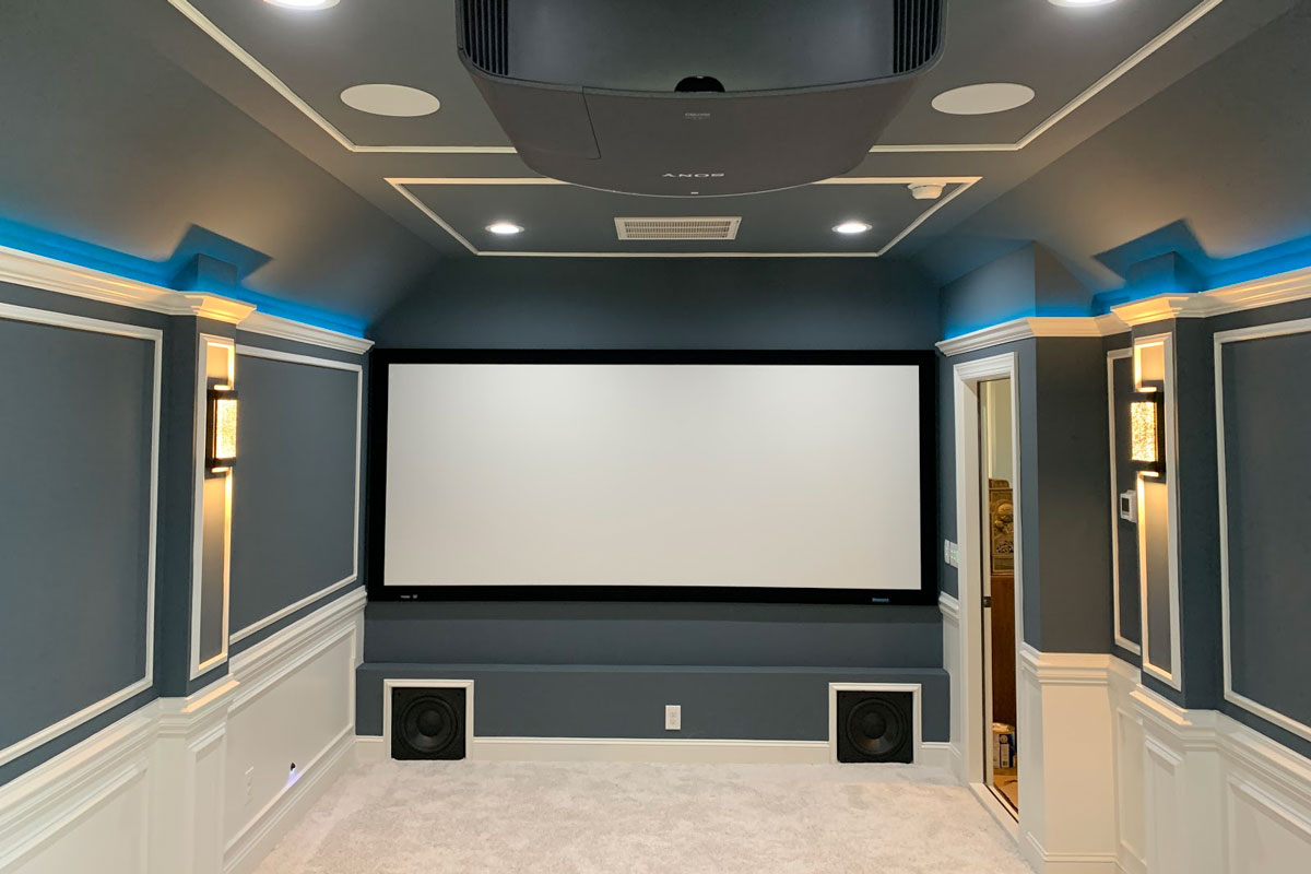 Full theater set up with projector and two speakers under theater screen.