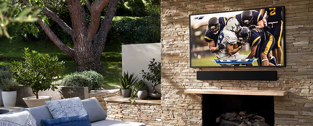 samsung terrace outdoor tv with soundbar mounted on brick patio wall above fireplace