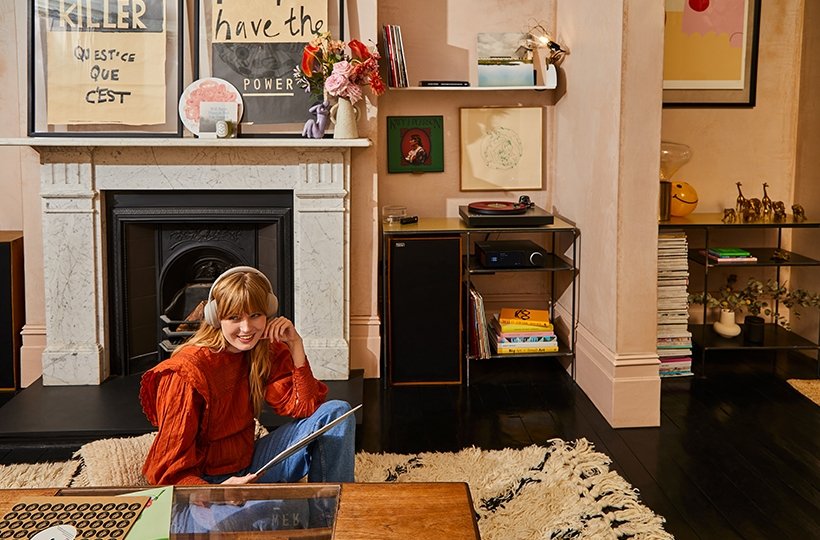 Woman wearing headphones sat on living room floor choosing records