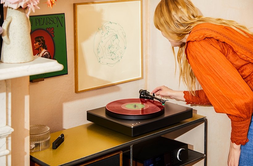 woman lowering stylus onto alva st turntable with red record